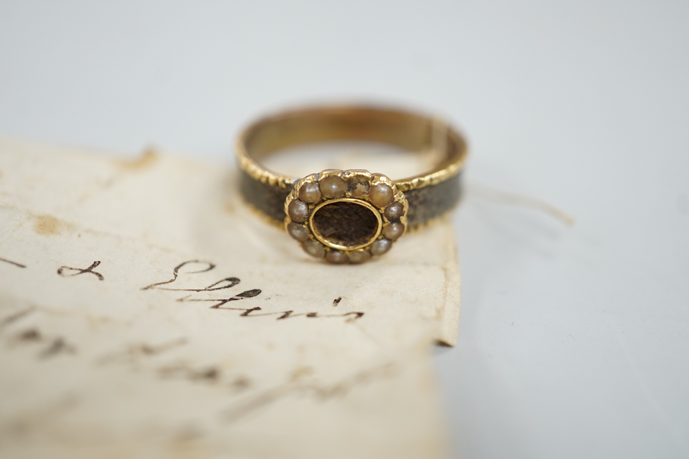 A 19th century yellow metal, split pearl and plaited hair set mourning ring, size O, gross weight 2.9 grams.